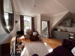 a living room with a couch and a kitchen at The Cottage in Dunblane