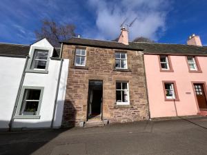 an old brick house with white and pink at The Cottage in Dunblane