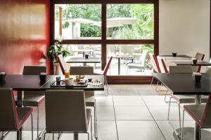 um restaurante com mesas e cadeiras e uma grande janela em ibis Auch em Auch