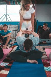 a woman is doing a yoga pose with a man at Surf capitain in Tamraght Ouzdar