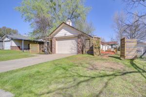 ein Haus mit einer Garage und einem Rasenplatz in der Unterkunft Barling Vacation Rental Fenced-In Yard with Hot Tub 