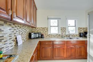 a kitchen with wooden cabinets and a sink at Sunny California Retreat Near Knotts Berry Farm! in Long Beach