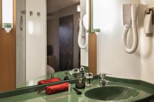 un bagno con un lavandino verde e uno specchio di ibis Auch ad Auch