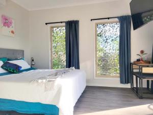 um quarto com uma cama grande e 2 janelas em Beachside One Bedroom Flat Retreat em Maroochydore