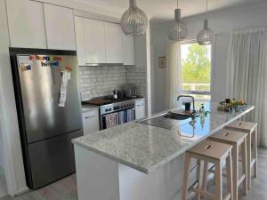 a kitchen with a stainless steel refrigerator and white cabinets at Beachfront 4 Bedroom Home in Nepean Bay in Nepean Bay