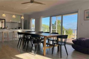 una sala da pranzo e una cucina con tavolo e sedie di Beachfront 4 Bedroom Home in Nepean Bay a Nepean Bay