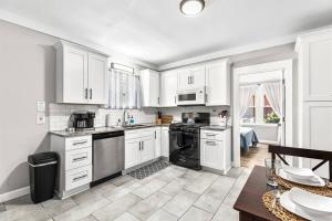 a kitchen with white cabinets and black appliances at Modern, Rustic Farmhouse Apartment near Downtown in Mount Clemens