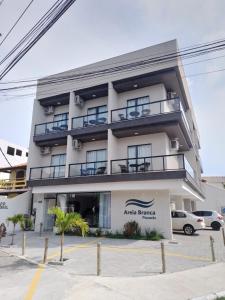 un bâtiment avec des voitures garées devant lui dans l'établissement Pousada Areia Branca, à Arraial do Cabo