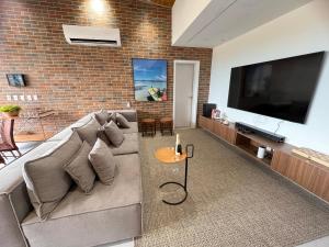 ein Wohnzimmer mit Couch und Flachbildfernseher in der Unterkunft Milagres Hospedagens - Cobertura Rota 206 - Capela & Praia in São Miguel dos Milagres