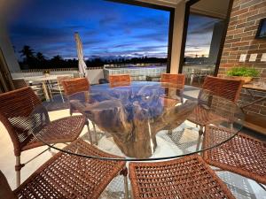 ein Glastisch mit Stühlen und ein Baumstumpf in der Unterkunft Milagres Hospedagens - Cobertura Rota 206 - Capela & Praia in São Miguel dos Milagres