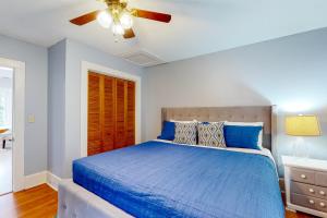 - une chambre avec un lit bleu et un ventilateur de plafond dans l'établissement Tryon Cottage, à Tryon