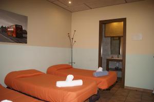 Dos camas naranjas en una habitación con un autobús rojo en HOTEL FAMILIAR BAGA, en Bagá