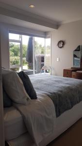 a bedroom with a large bed with a window at Mangawhai Heads apartment in Mangawhai