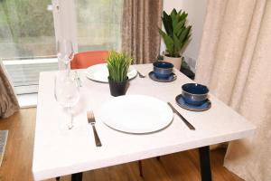 a white table with plates and wine glasses on it at Crayford, Super Cosy 2-Bed Apartment in Dartford +5 photos