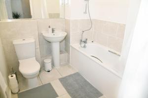 a bathroom with a toilet and a sink and a bath tub at Crayford, Super Cosy 2-Bed Apartment in Dartford