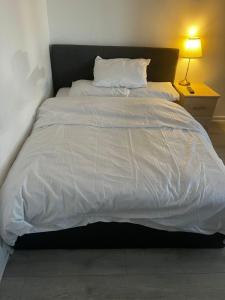 a large white bed in a room with a lamp at 13 Clifton Court - Lovely 2 bedroom flat with patio in Finsbury Park in London