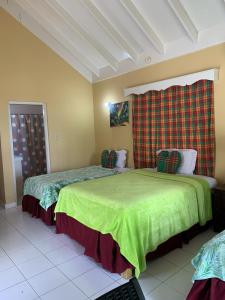 two beds in a room with a green blanket at Family Comfort in Jamaica - Enjoy 7 miles of White Sand Beach! villa in Negril