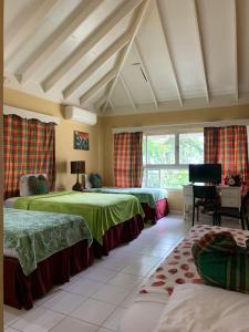 1 Schlafzimmer mit 2 Betten, einem Schreibtisch und einem Fenster in der Unterkunft Family Comfort in Jamaica - Enjoy 7 miles of White Sand Beach! villa in Negril