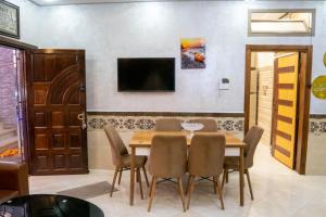 - une salle à manger avec une table, des chaises et une télévision dans l'établissement Riad dar asalam, à Agadir