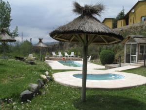 una sombrilla de paja con una piscina en un patio en Cabañas Los Arreboles en Potrerillos