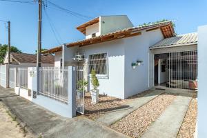 a white house with a fence in front of it at Linda casa a 150m da praia e prox ao Beto Carrero in Penha