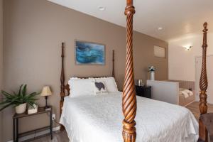 a bedroom with a four post bed with a white bedspread at Wharf Master's Inn in Point Arena