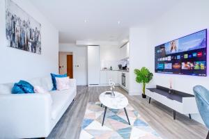 Luxe Apartment by Excel في لندن: غرفة معيشة مع أريكة بيضاء وتلفزيون