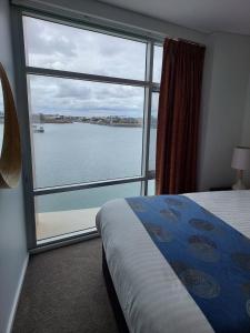 a bedroom with a large window with a view of the water at Wallaroo Marina Executive Apartments in Wallaroo