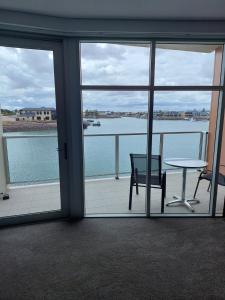 a room with a table and chairs and a view of the water at Wallaroo Marina Executive Apartments in Wallaroo