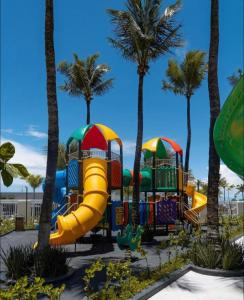 a playground with a slide and palm trees at Salinas Premium Resort Apto completo in Salinópolis