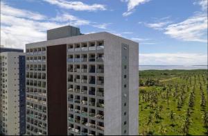 a tall building in front of a field of trees at Salinas Premium Resort Apto completo in Salinópolis