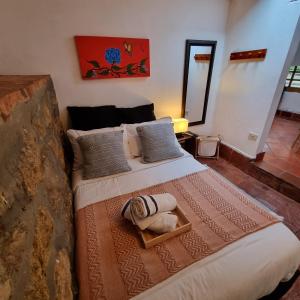 1 dormitorio con 1 cama grande con manta y almohadas en Casita Artemisa - Tiny House Romántica y Mágica en Villa de Leyva