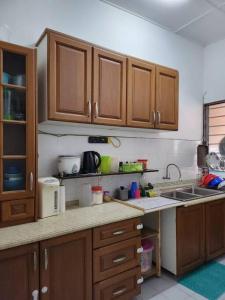uma cozinha com armários de madeira e um lavatório em D'Haja 6 KLIA Sepang with 3 AC & FREE Wi-Fi em Banting