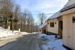 une route enneigée à côté de deux bâtiments avec de la neige au sol dans l'établissement Condo #5 Slopeside One Bedroom with Sauna and Hot tub, à Killington