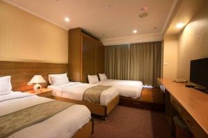 Habitación de hotel con 2 camas y TV de pantalla plana. en APAC Lukang Resort, en Lukang
