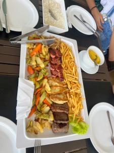 una bandeja de comida con carne y patatas fritas en una mesa en Salinas Premium Resort Apto completo, en Salinópolis