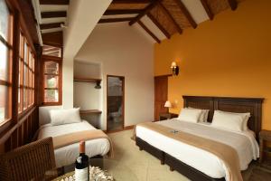 two beds in a room with yellow walls at Hotel Campanario Real in Villa de Leyva