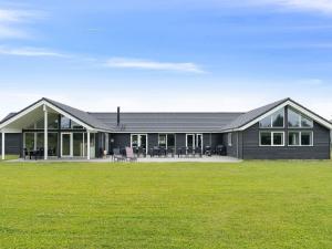 une maison noire avec une grande cour devant elle dans l'établissement Holiday home Grenaa XVIII, à Grenå