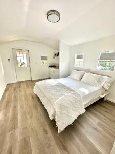 a white bedroom with a large bed and wooden floors at Beach guests house in Miami