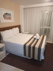 a bedroom with a white bed with a striped blanket at Apart-Hotel Premium in Brasilia