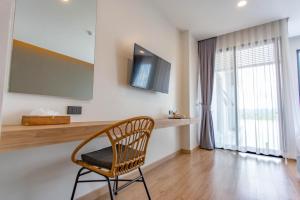 a chair in a room with a television on a wall at Chewa Khong Nakhon Phanom - SHA Certified in Nakhon Phanom