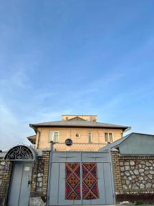 a house with a gate and a building in the background at Ayla Hostel in Osh