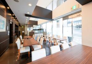 ein Restaurant mit Holztischen und weißen Stühlen in der Unterkunft APA Hotel Midosuji-Honmachi-Ekimae in Osaka
