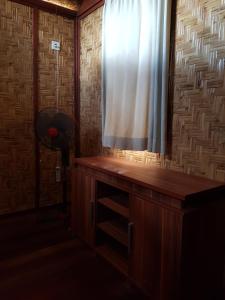 a room with a window and a wooden desk with a curtain at Bidara Cottage in Labuhanpandan