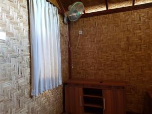a room with a fan and a wall with a window at Bidara Cottage in Labuhanpandan