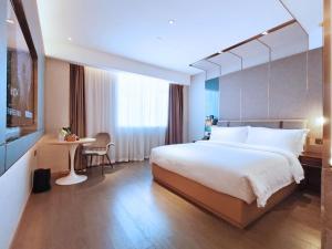 広州市にあるPaco Hotel Guangzhou South Railway Station Panyu Changlong Branchの大きなベッドとテーブルが備わるホテルルームです。