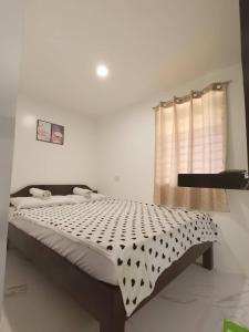 Schlafzimmer mit einem Bett mit einer schwarzen und weißen Bettdecke in der Unterkunft Villa Kendra in Moalboal