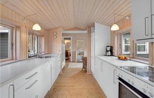 a kitchen with white cabinets and a wooden ceiling at Holiday Home H in Højby