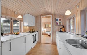 a kitchen with white cabinets and a wooden ceiling at Holiday Home H in Højby