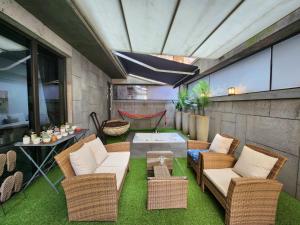 patio con sillas de mimbre, mesa y bañera en JS Boutique Hotel en Hwaseong